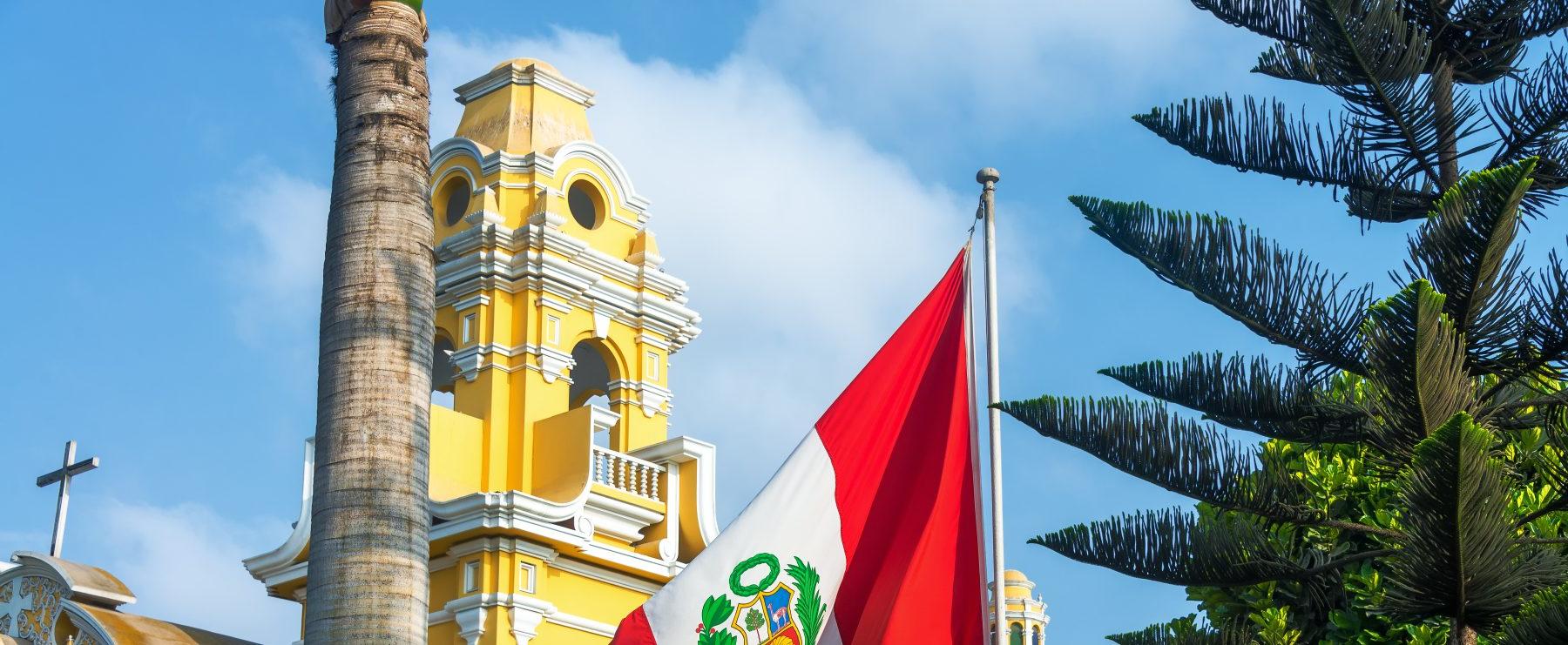 秘鲁国旗在黄色建筑前飘扬